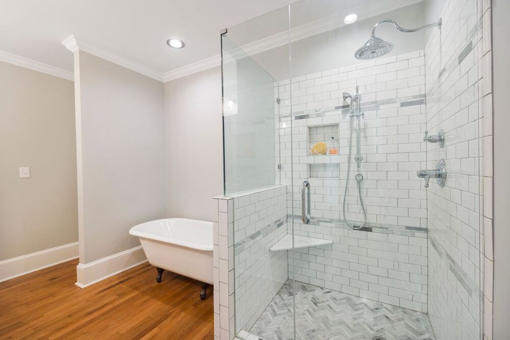 Cancel de baño de vidrio con panel fijo y puerta junto a una tina independiente