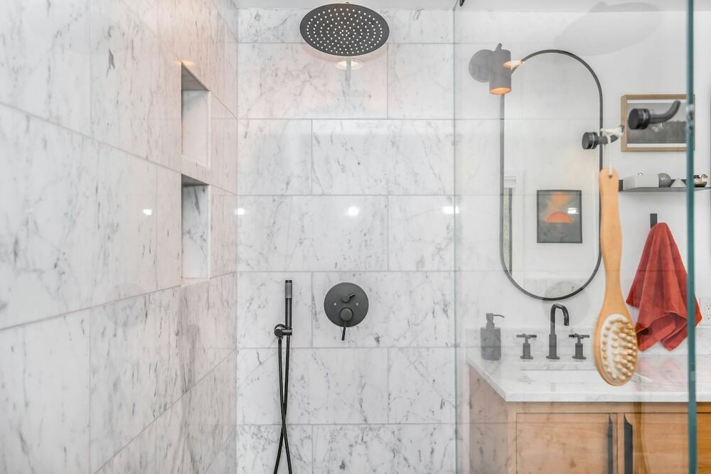 Ducha con vidrio templado transparente y paredes de azulejo de mármol blanco